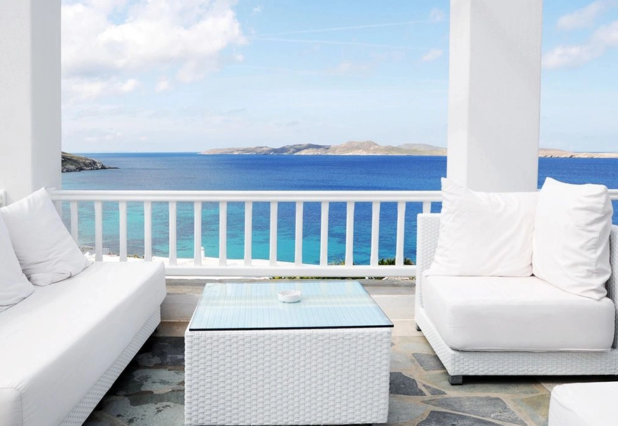 A balcony with a view of the ocean and a white couch.