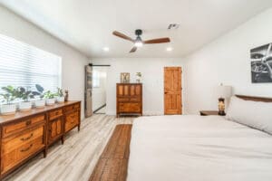 Minimalist bedroom with wooden furniture and plants.