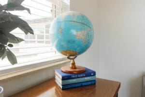 Globe on stacked books near window.