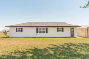 Single-story white house with grassy yard.