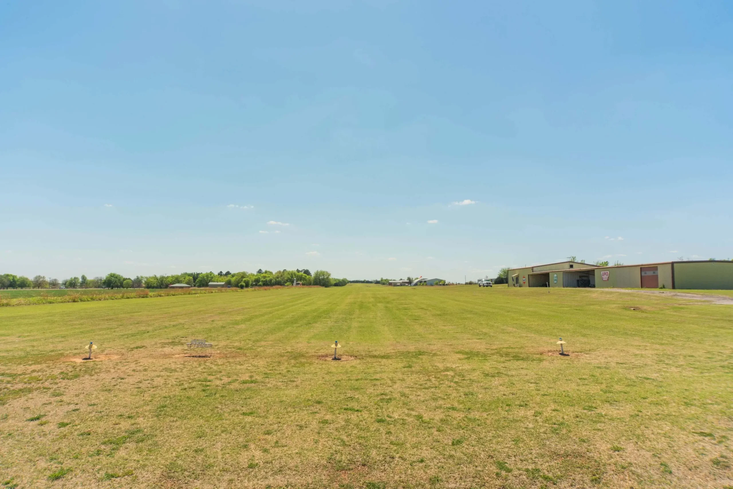 Grass airstrip under clear blue sky.